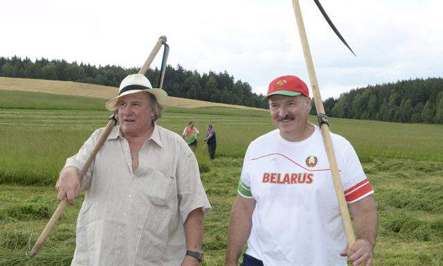Belarus´ President Lukashenko and French actor Depardieu carry scythes as they walk at Ozerny presidential residence outside Minsk