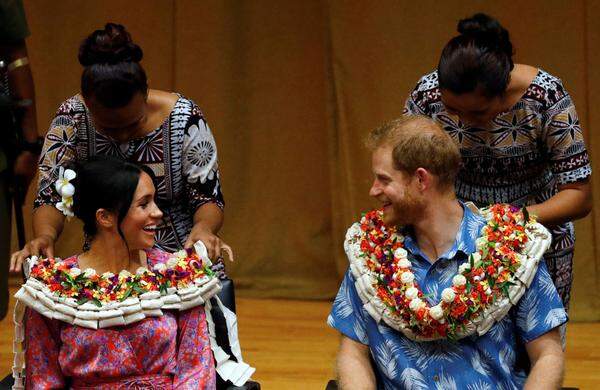 Dort hielt Herzogin Meghan eine Rede, außerdem wurde das royale Paar mit Blumengirlanden geschmückt, was ihre farbenfrohen Outfits (die Herzogin trug ein Kleid von Figue Frederica) komplettierte.