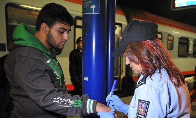 Eine Polizistin schreibt mit Filzstift Nummern auf die Hand eines Flüchtlings.