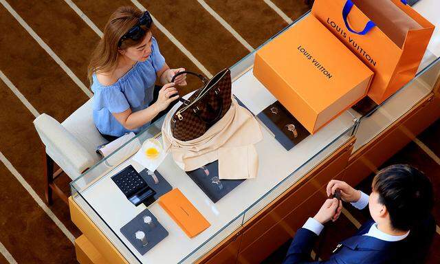 A woman buys a Louis Vuitton bag in a shop in Singapore