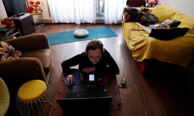 French yoga teacher Nadege Lanvin does a live broadcast of her yoga lesson with laptop during the closure of her yoga center in Paris