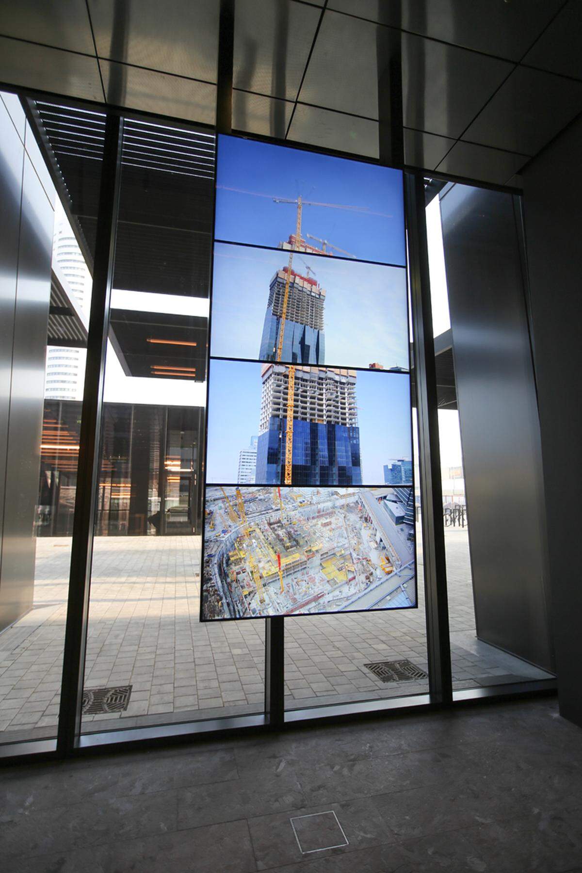 In der Eingangshalle sind Bildschirme montiert, die den Bau des DC Tower im Zeitraffer zeigen.