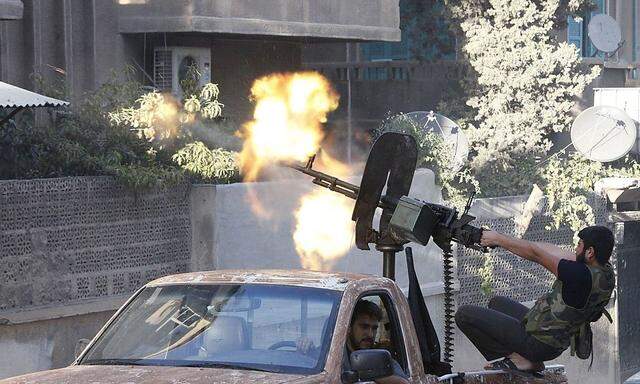 A member of Free Syrian Army open fire from his machine gun during clashes with Syrian Army forces in Aleppo