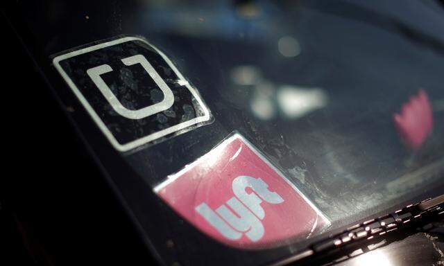 A driver displays Uber and Lyft ride sharing signs on his car windscreen in Santa Monica