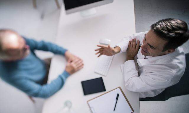 Top view of doctor talking to senior patient in medical practice model released Symbolfoto property