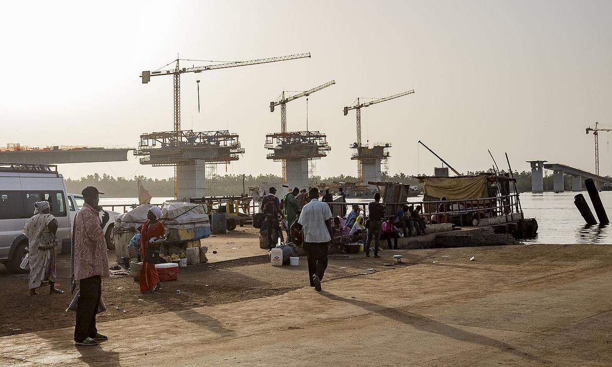 Wer auf dem Trans-Gambia-Highway von Ufer zu Ufer übersetzen will, muss noch die Fähre nehmen. Doch die Trans-Gambia-Bridge nimmt nach langen Blockaden Gestalt an. Die Beziehungen zwischen Gambia und das es umgebende Senegal haben sich verbessert.