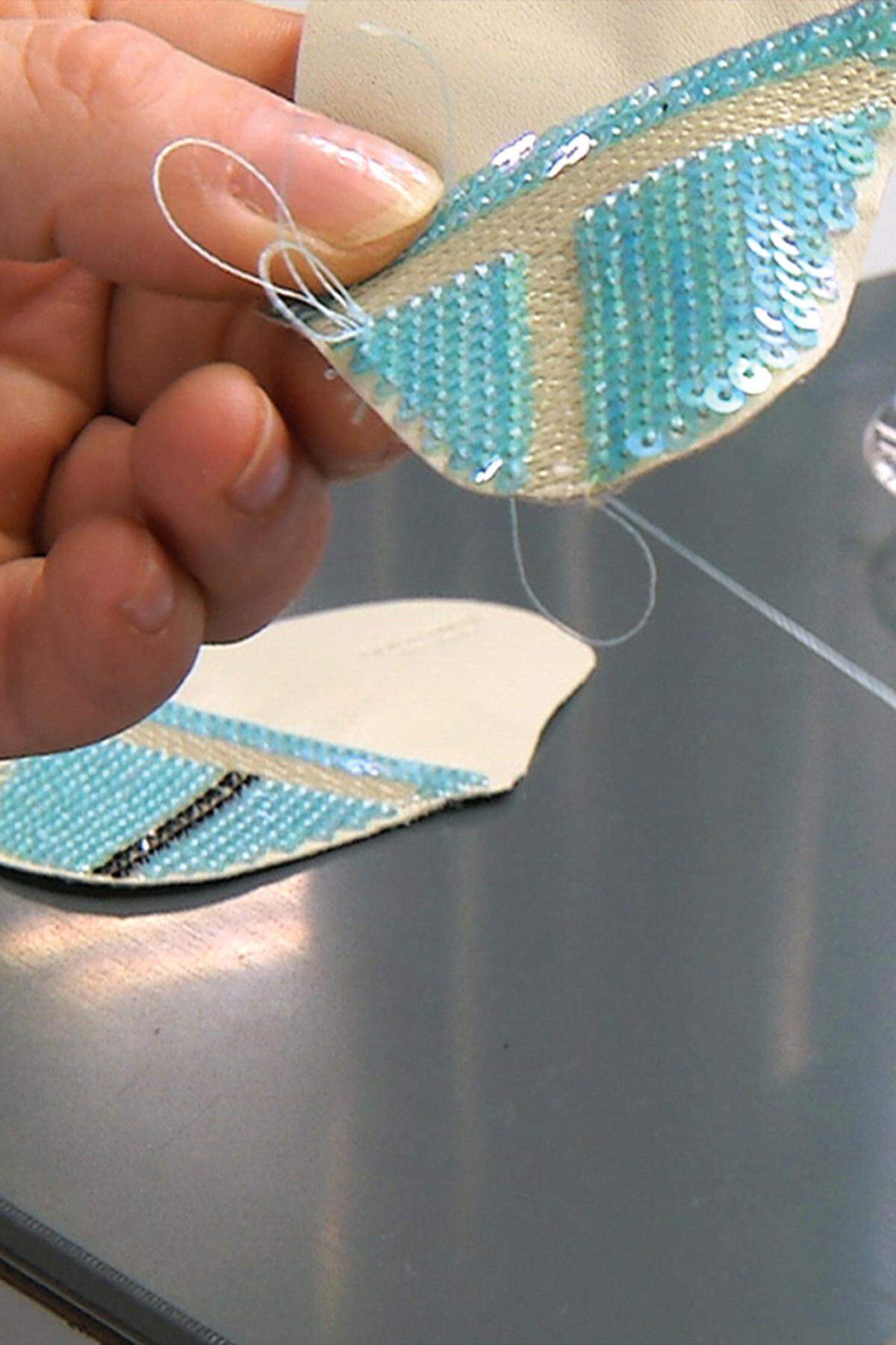 Händisch applizieren Näherinnen Pailletten und Kristalle auf das Nappaleder.