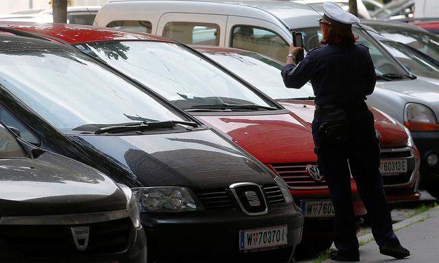 A traffic warden checks cars parked on a street in Vienna
