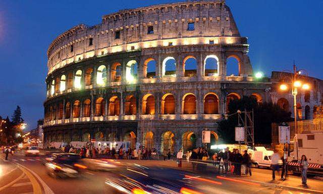Traffic zooms past Romes ancient Colosseum, glowing with golden lights to commemorate the victims ofs ancient Colosseum, glowing with golden lights to commemorate the victims of
