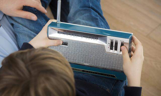 Father and son listening to an old radio model released Symbolfoto property released PUBLICATIONxINxGERxSUIxAUTxHUNxONL