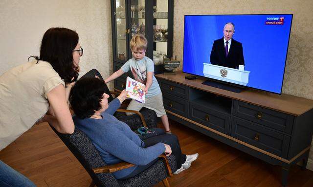 Eine russische Familie sieht sich Putins Ansprache im Fernsehen an.