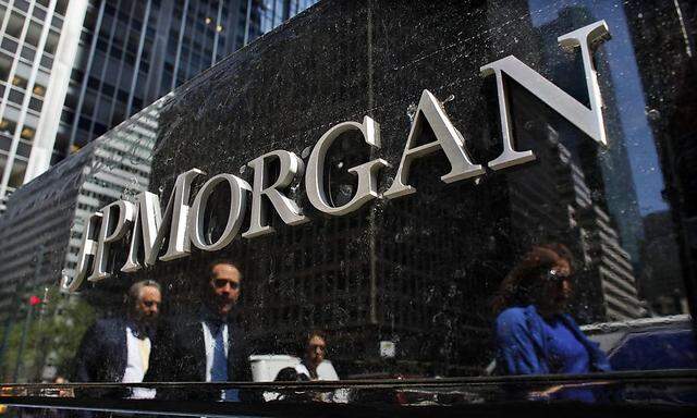 File of commuters reflected in stone as they walk past the JP Morgan headquarters in New York