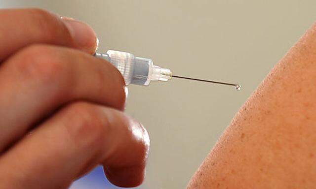 ARCHIV - Ein Arzt spritzt einer Patientin am 10. Oktober 2008 in Dresden zur Impfung ein Grippeschutz