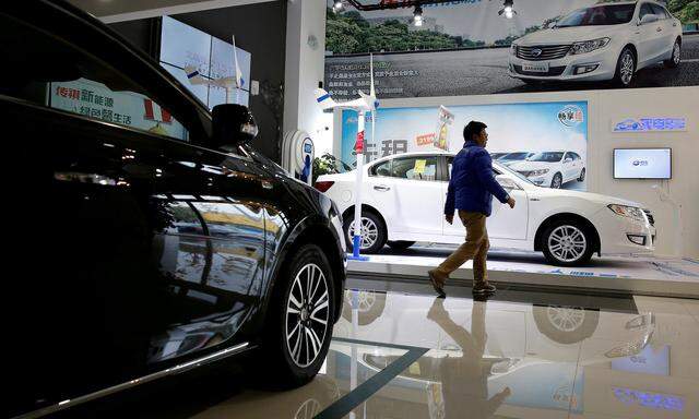 FILE PHOTO:  A man walks at an electric car dealership in Shanghai