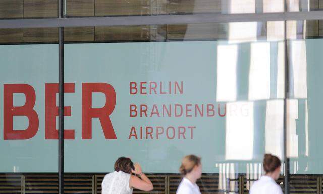 Zuschauer blicken durch eine Glasscheibe in das Terminal des Flughafen Berlin Brandenburg BER beim K