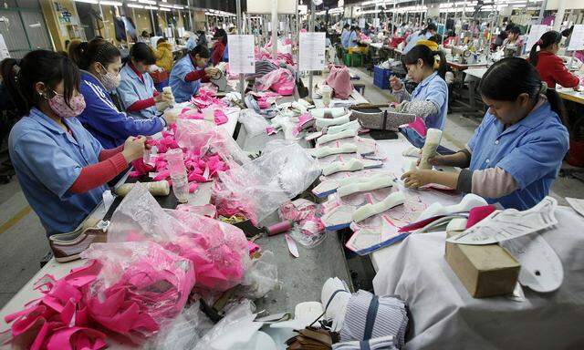 Employees work on an assembly line at a shoe factory in Tan Lap village
