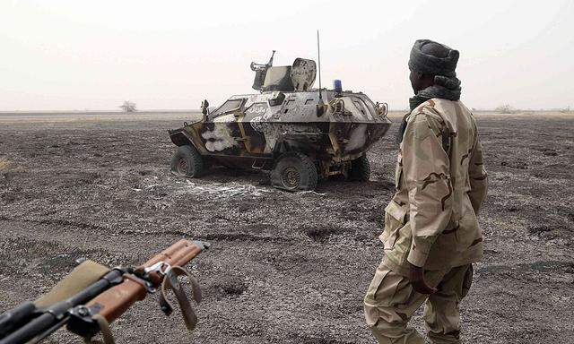 A Chadian soldier walks past an armored vehicle that the Chadian military said belonged to insurgent group Boko Haram that they destroyed in battle in Gambaru