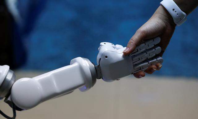 Chalermpon Punnotok, CEO of CT Asia Robotics gives a hand to a robot during an interview with Reuters in Bangkok