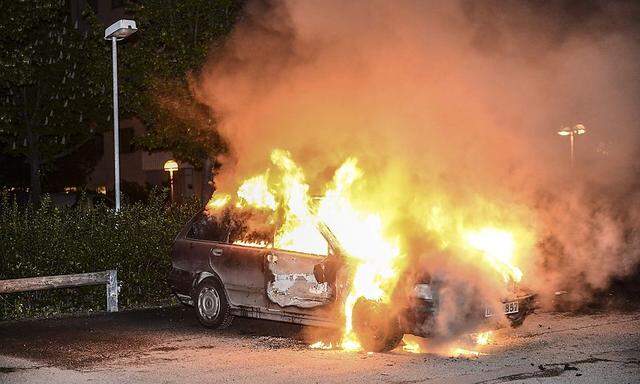 A car set on fire burns following riots in the Stockholm suburb of Kista