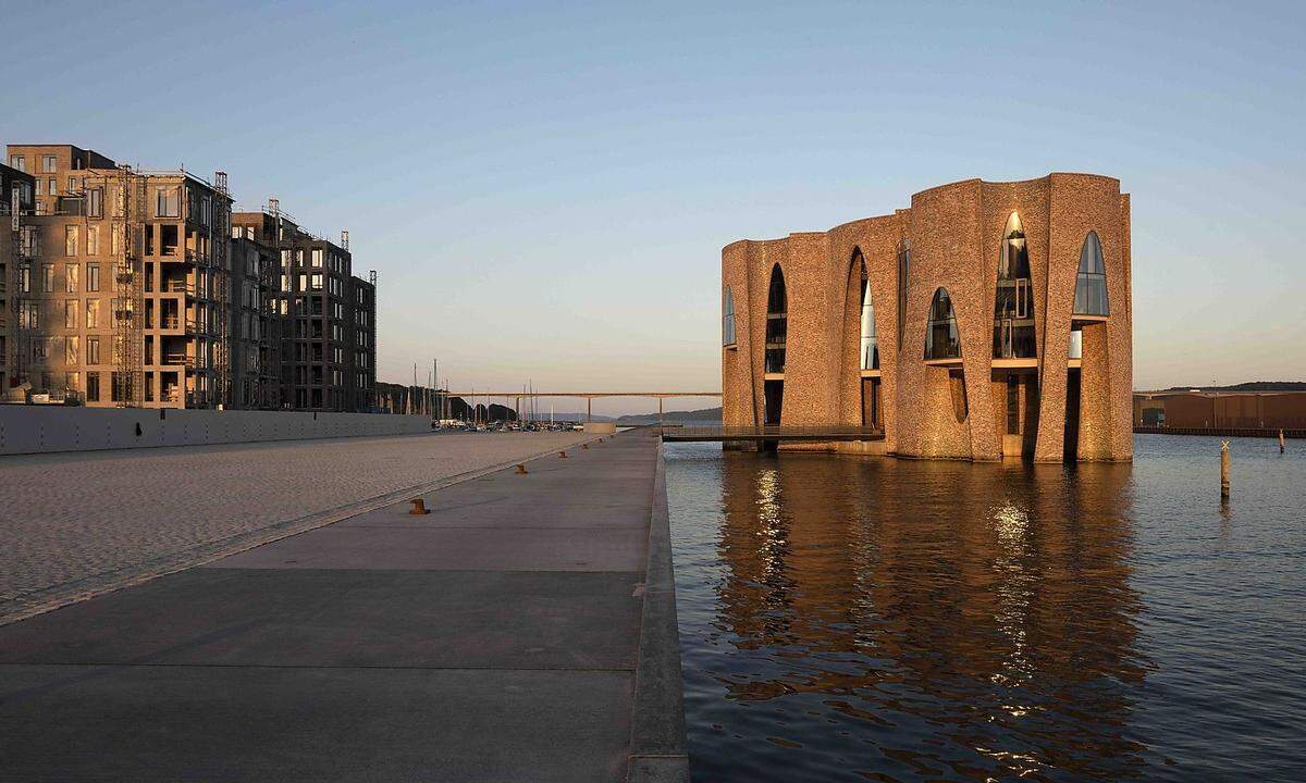 Im dänischen Jütland erhebt sich "Fjordenhus", der neue Firmensitz der Investorengruppe Kirk Kapital, aus dem Wasser. Gestaltet vom isländisch-dänischen Künstler Ólafur Elíasson, lieferte die österreichische Firma Waagner-Biro die gewölbten Stahl-Glas-Fassaden, die gebogenen Türen sowie die drei Haupttreppen inklusive Aufzüge. Die Kunstwerke im Erdgeschoß sind öffentlich zugänglich. (red., 27. 7. 2018)