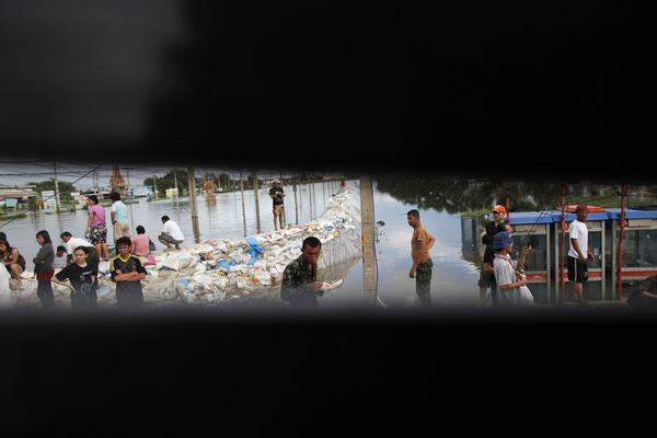 Im Bild: In der Provinz Ayutthaya warten Menschen auf einer Insel aus Sandsäcken auf einen Lkw.