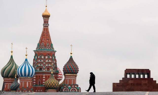 Police officer walks along the Red Square with St. Basil's Cathedral and Lenin Mausoleum seen in the background, in Moscow