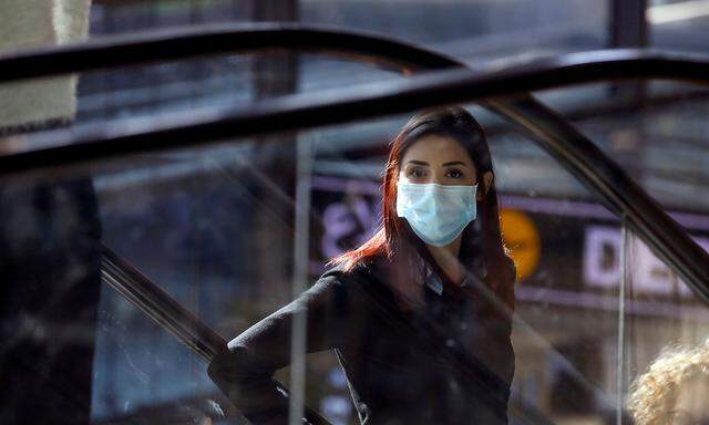 FILE PHOTO: A woman wearing a mask looks on at a terminal at Ben Gurion International airport in Lod, near Tel Aviv, Israel