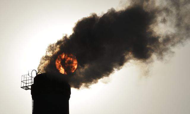 File photo of the sun seen behind smoke billowing from a chimney of a heating plant in Taiyuan