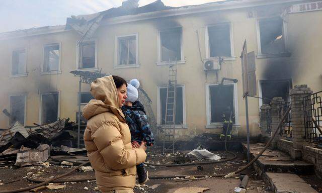 Eine Anwohnerin geht mit ihrem Kind am 25. Februar 2024 an dem durch einen russischen Raketenangriff zerstörten Bahnhof in Kostjantyniwka in der Region Donezk vorbei.