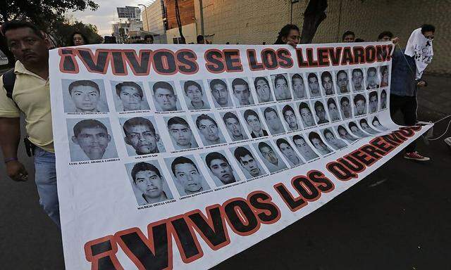 Protesters hold up a banner with pictures of missing students from the Ayotzinapa Teacher Training College, during a march supporting them in Mexico City