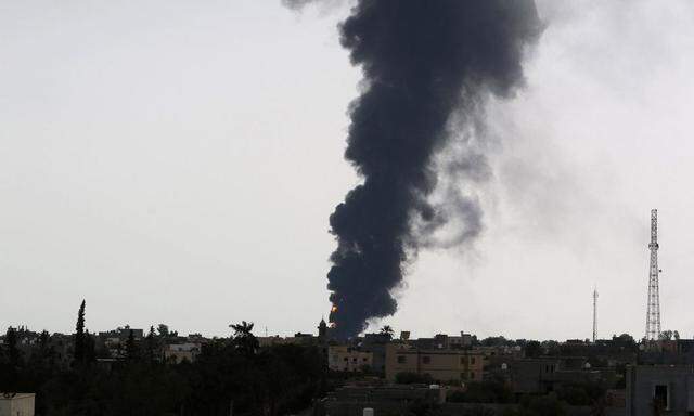 Plumes of smoke rise in the sky after a rocket hit a fuel storage tank near the airport road in Tripoli, during clashes between rival militias