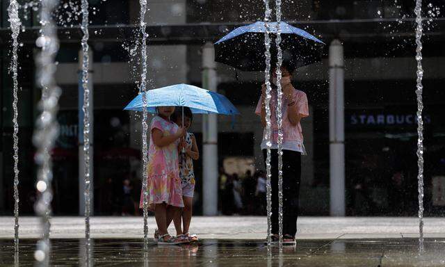Steigende Temperaturen. Die Menschen in Hongkong versuchen, sich vor der Hitze zu schützen. 