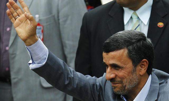 Iran's President Ahmadinejad waves during a ceremony to swear Venezuela's President Maduro into office, in Caracas