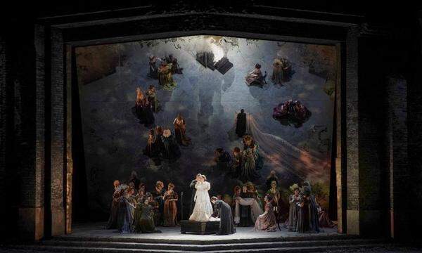 Ein geneigter Spiegel als Bühnenhintergrund sowie opulente historische Kostüme sorgen bei dieser Medea in der Athener Oper für einen malerischen Effekt.