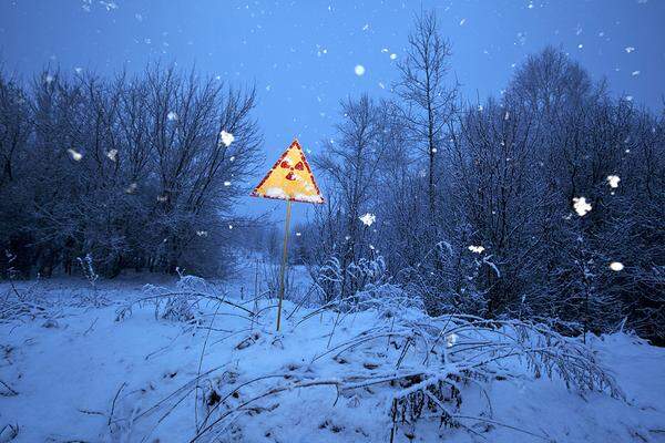 Ein Schild warnt in der Nähe von Prypjat vor der radioaktiven Strahlung. Es steht im seltsamen Gegensatz zu der idyllischen Winterlandschaft.  (c) Gerd Ludwig/ Institute/ Edition Lammerhuber