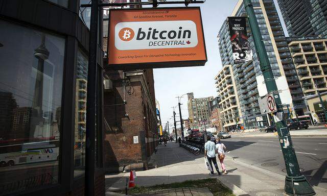 People walk by a 'Bitcoin Decentral' sign in Toronto