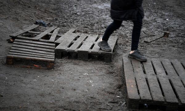 Belarus Poland Border Refugees 6706900 28.11.2021 A refugee walks on pallets at the Bruzgi logistics centre providing a