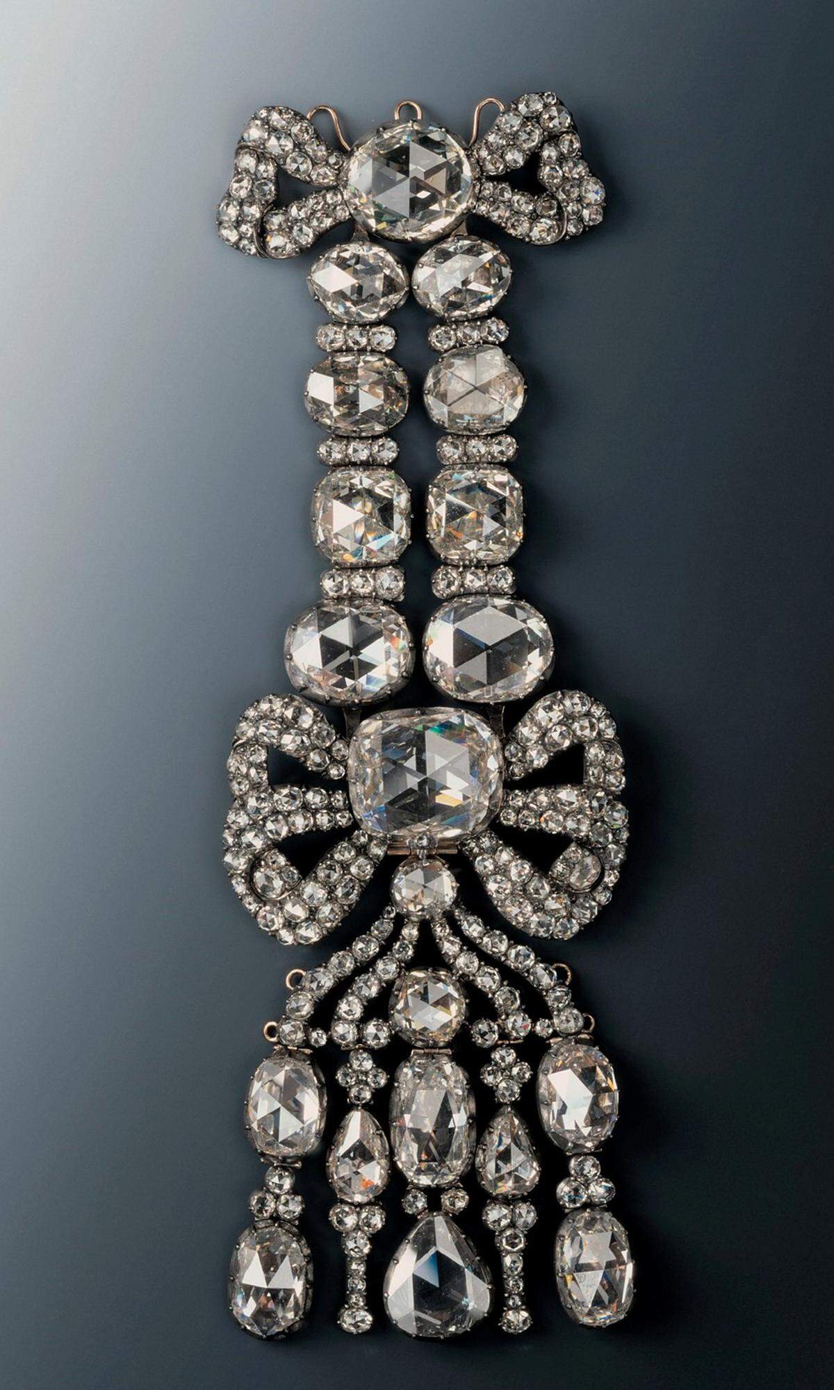 Dies ist eine sogenannte Achselschleife - auch als "Epaulette" bezeichnet - ist mit 20 großen und 216 kleinen Diamanten besetzt. Sie wurde früher mit Fixierungen an der Kleidung angebracht.