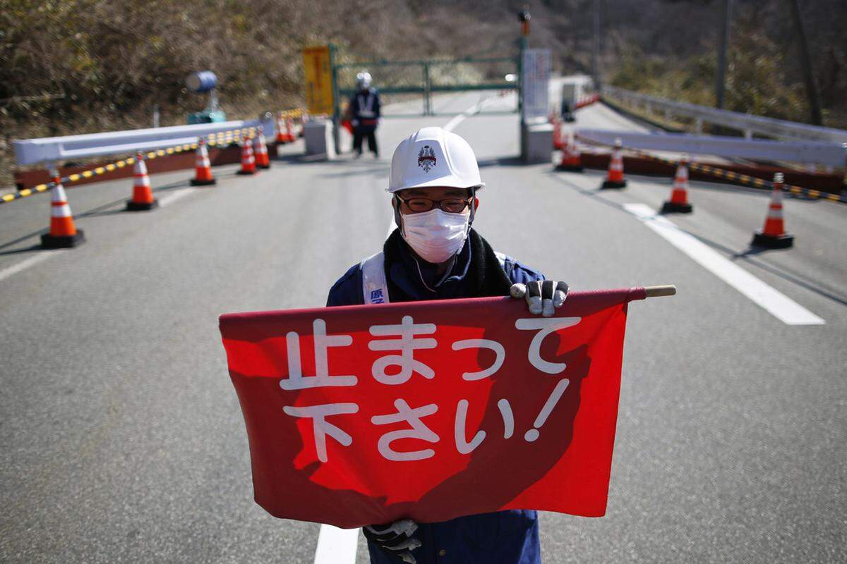 "Bis hierhin und nicht weiter" signalisiert die rote Flagge an der Grenze zum verbotenen Gebiet zwischen Okuma und Tamura - zwischen Sperrgebiet und wiedergewonnener Heimat in der Nähe des im März 2011 havarierten Atomkraftwerks Fukushima Daichii.