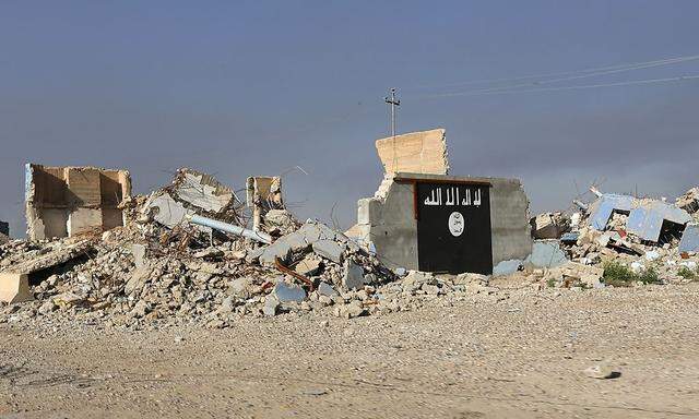 Symbolbild: Eine Flagge, wie sie häufig von der der Terrororganisation IS verwendet wird, auf einem zerstörten Haus im Irak. 