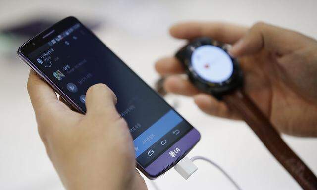 A man tries out a LG Electronics' G3 smartphone and G Watch R during the 2014 Korea Electronics Show in Goyang