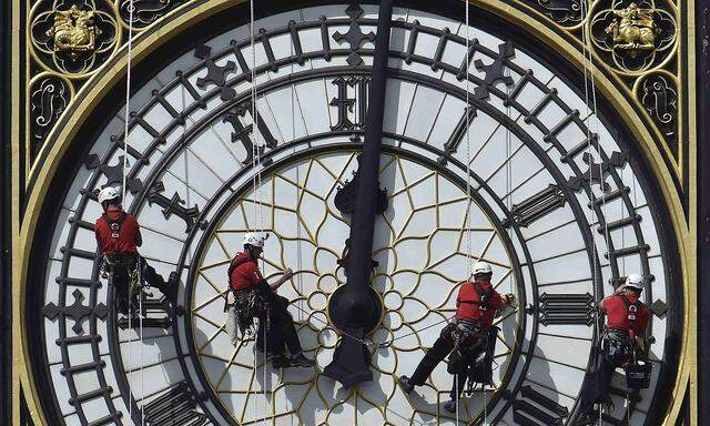 Cleaners abseil down one of the faces of Big Ben, to clean and polish the clock face, above the Houses of Parliament, in central London