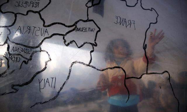 Ein Flüchtlingskind betrachtet eine Karte von Europa in einem provisorischen Zelt in einem Flüchtlingslager.