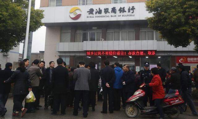 People gather in front of a branch of Rural Commercial Bank of Huanghai in Yancheng, Jiangsu province