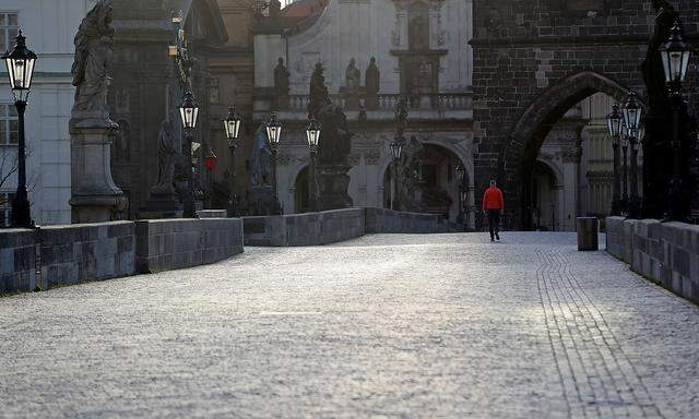 A man walks across an empty medieval Charles Bridge in Prague