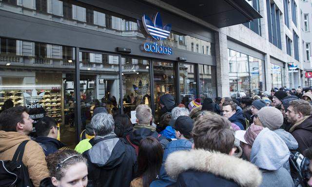 Menschen stehen Schanlge vor dem Adidas Store in Berlin Mitte um die Schuhe Adidas EQT Support 93 Be