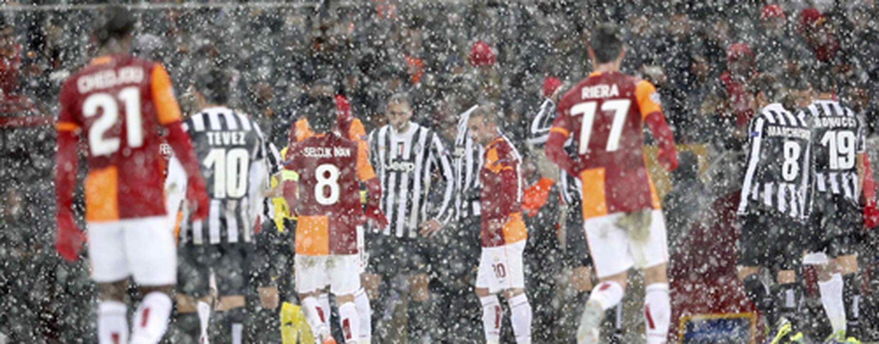 Players of Galatasaray and Juventus walk out of the pitch as their match is paused for 20 minutes due a heavy snowfall during their Champions League soccer match in Istanbul