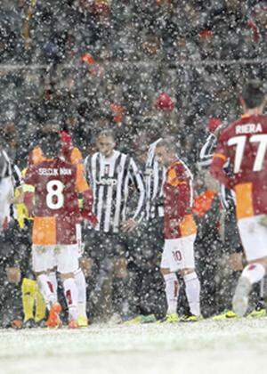 Players of Galatasaray and Juventus walk out of the pitch as their match is paused for 20 minutes due a heavy snowfall during their Champions League soccer match in Istanbul