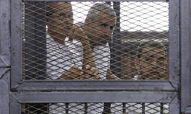 File photo of Al Jazeera journalists Greste, Fahmy and Mohamed behind bars at a court in Cairo