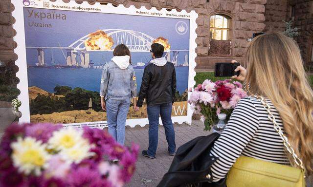  Freude in Kiew über Rückschlag für Russland. Ukrainer bewundern ein Bild der brennenden Krim-Brücke.